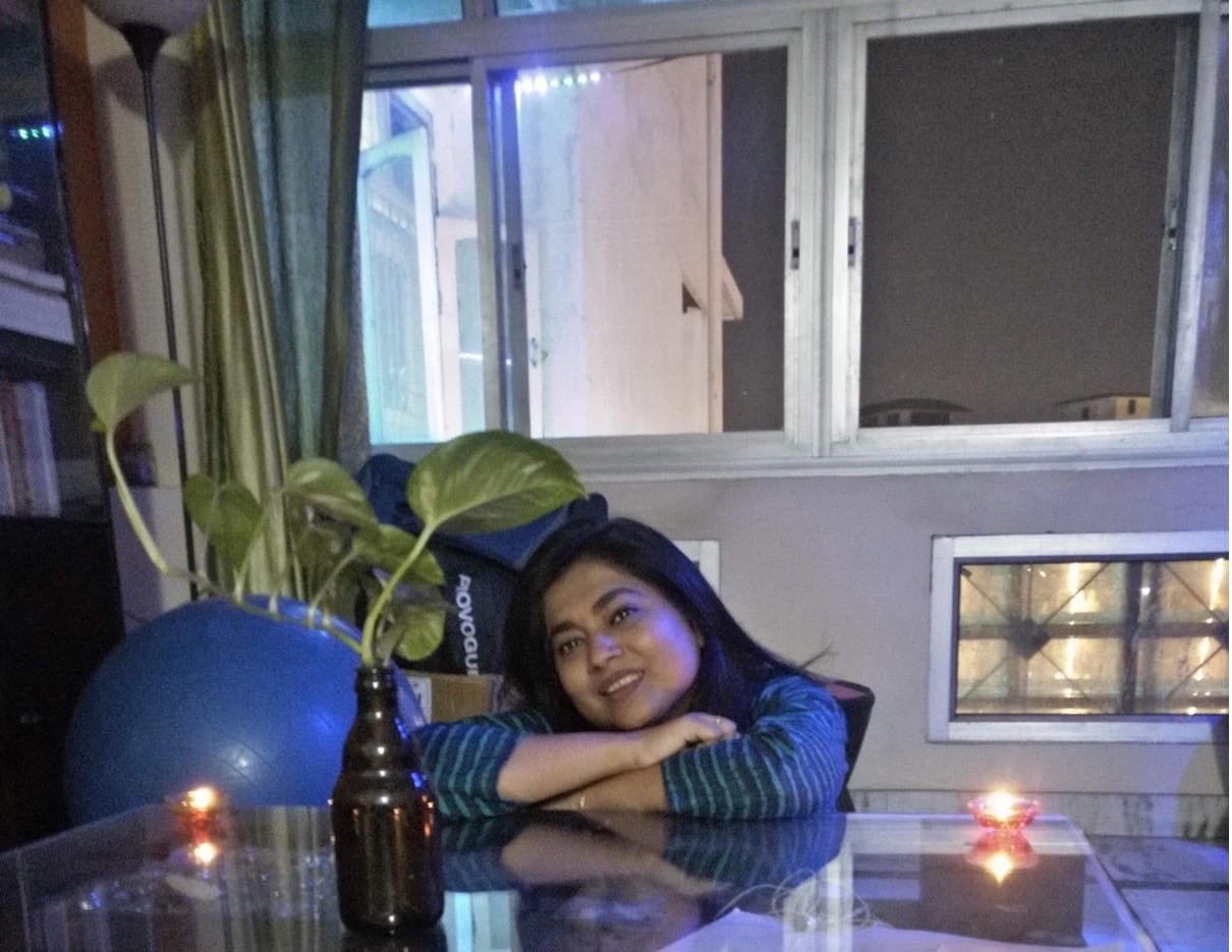 default-491 Large windows can be seen in the background as a woman sits, her arms resting on a clear kitchen table.